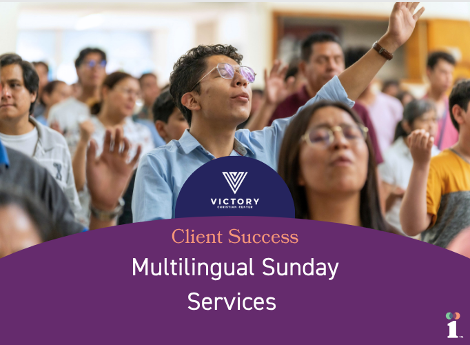 A group of people gathered indoors with raised hands, appearing engaged in a shared moment of worship