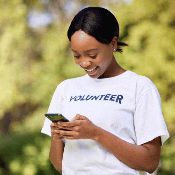 A young female volunteer looking at her smartphone and smiling
