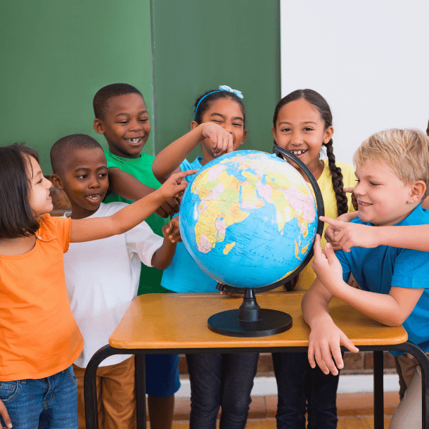 A group of school children standing around a globe and pointing at different countries