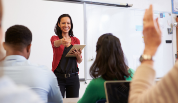 Female teacher holding a mobile tablet pointing at a student