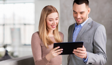 Two business people reading transcript from tablet